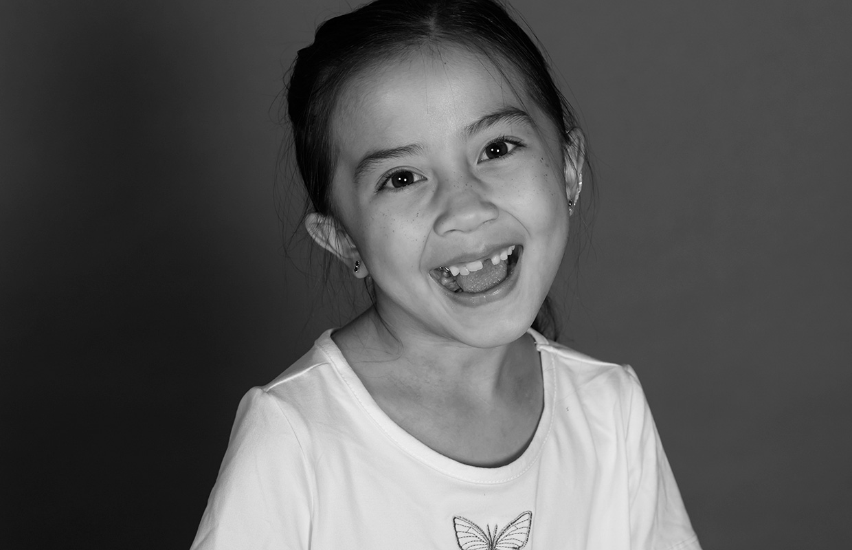 Black and white image of smiling young girl in white t-shirt