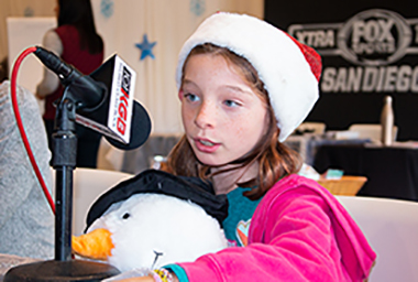 Young girl wearing Santa hat speaks into radio microphone