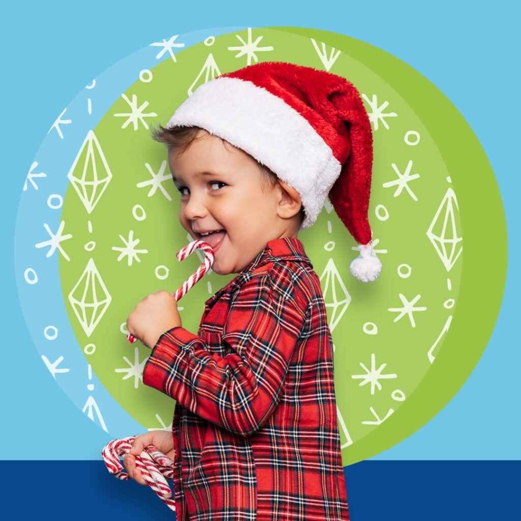 Boy wearing santa hat, licking a candy cane.