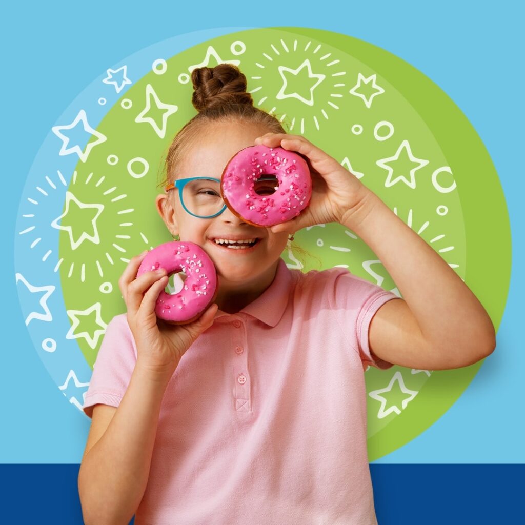 Girl wearing glasses, holding donuts over her eyes