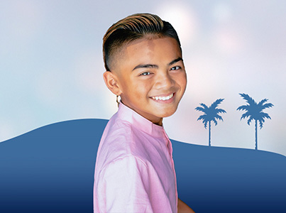 smiling boy wearing pink shirt with blue background