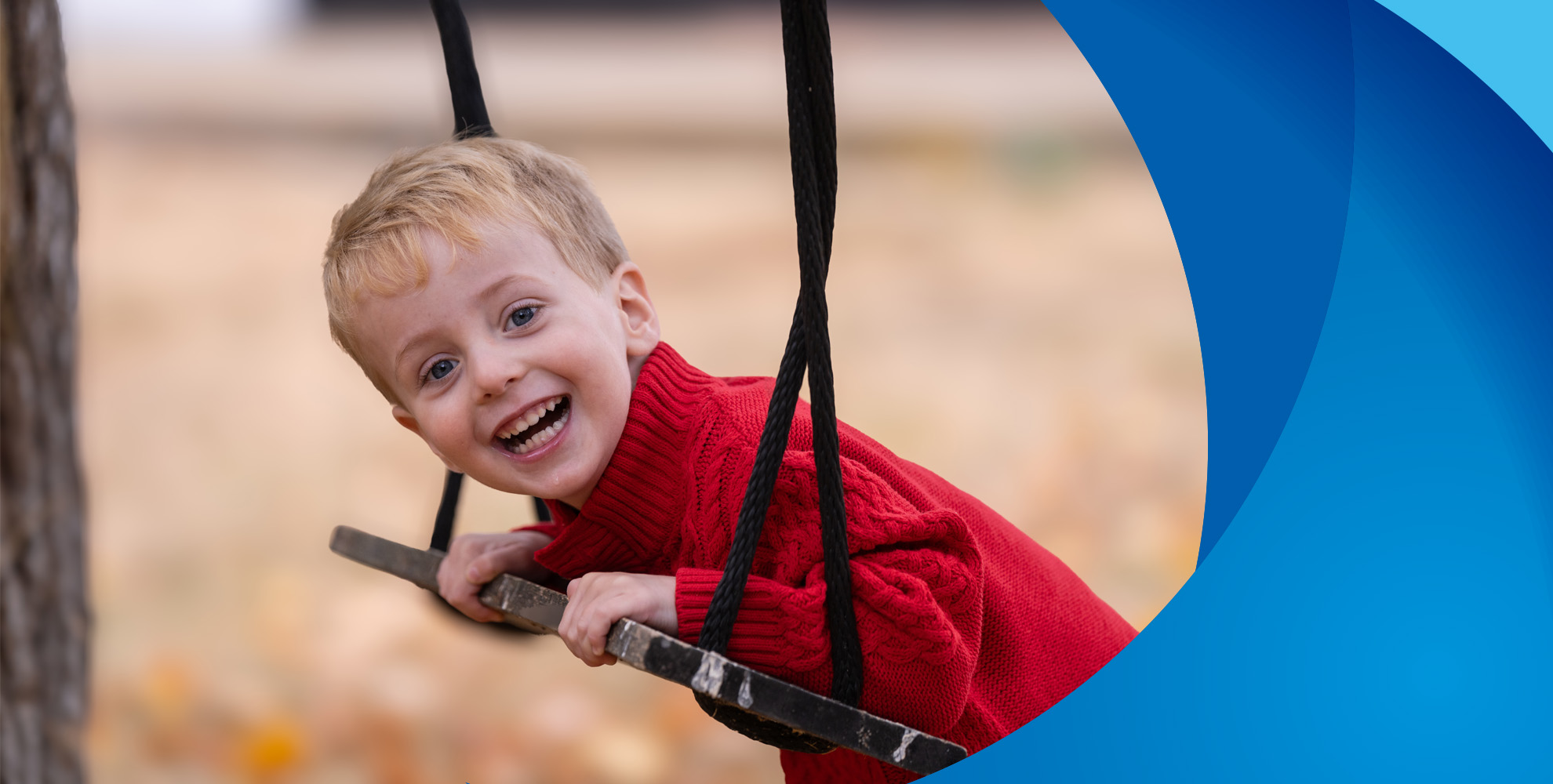 young boy smiling and leaning on swing