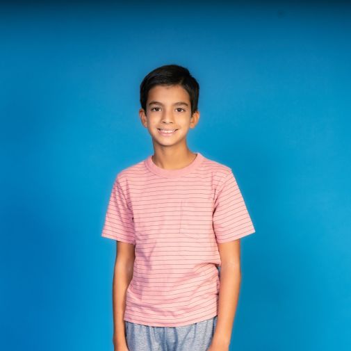 young boy wearing pink shirt with blue background