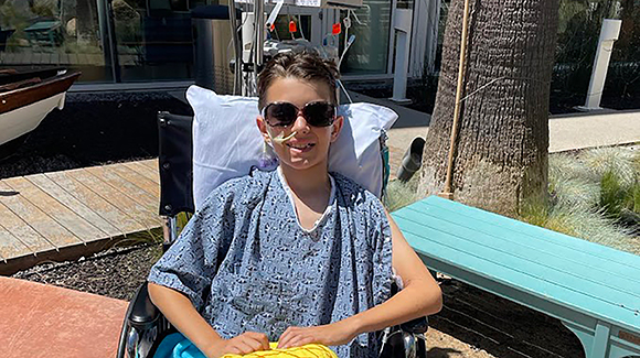 boy wearing sunglasses sitting outside in wheelchair