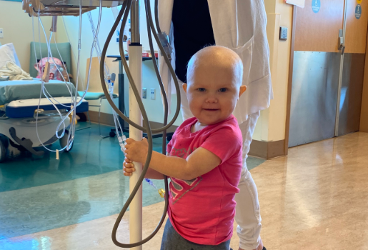 toddler girl holding onto iv pole