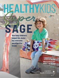 A boy sitting at the skatepark with his board
