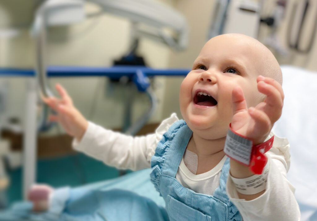 A smiling a baby sitting up on a gurney