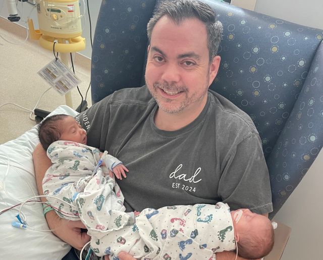 Father holding newborn twins