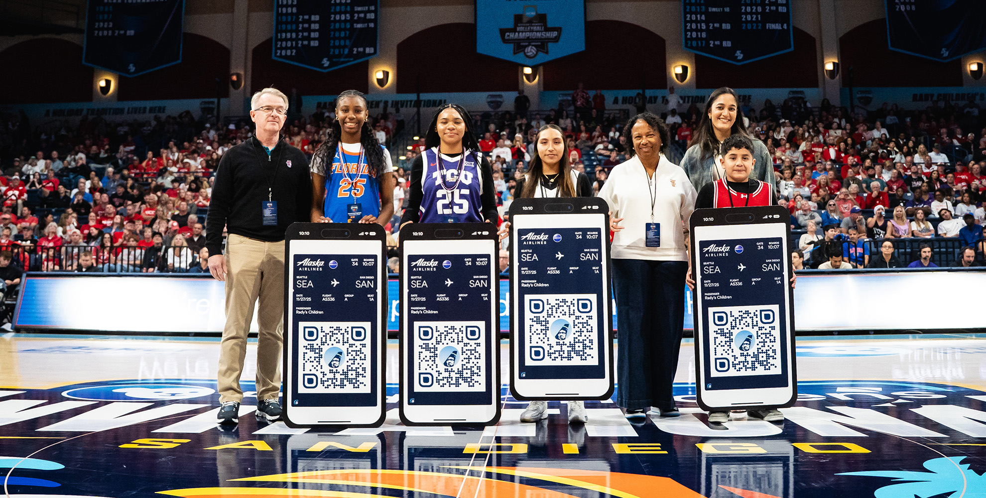 Group posing at sporting event with Alaska Airlines posters