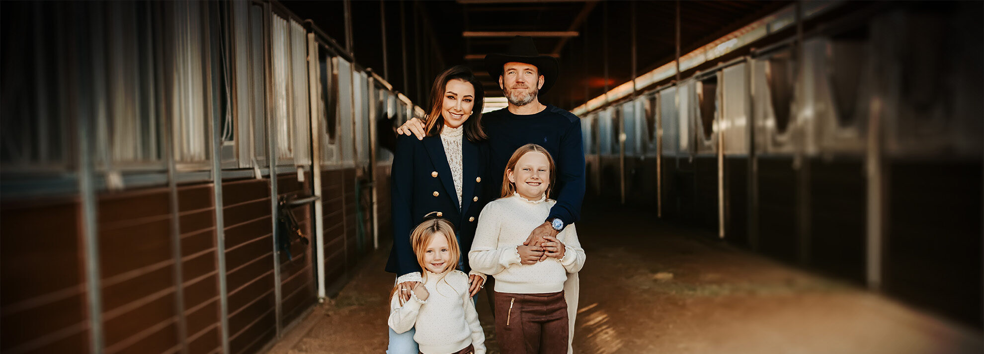 Mom, dad and two children posing for photo in horse stable