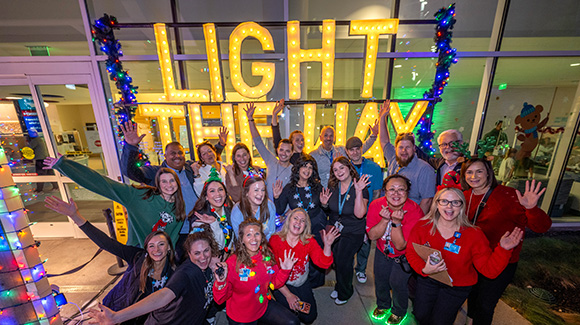 Group of people waving and smiling at Light the Way event.