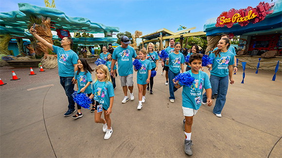 Group of families holding pom poms while starting the Walkabout at SeaWorld San Diego